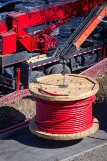 Big red cable coil, rises for installation at the city construction site, no people