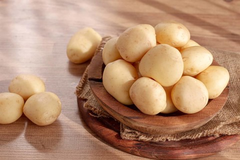 Boiled new potatoes, in a wooden bowl, on a rustic table, natural light, no people