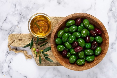 Chalkidiki olives, classic Greek green olives, in a bowl on a cutting board, top view, without