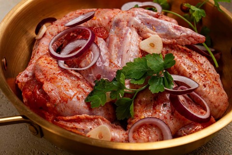 Chicken wings, in a brass saucepan, ready for cooking, grilling or baking, in a home kitchen, no