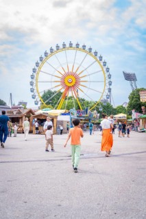 People on a square in an amusement park with a large Ferris wheel in the background, Olympiapark,