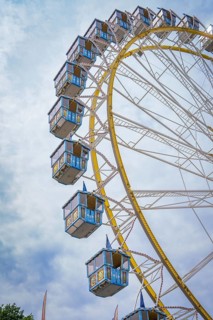 Ferris wheel with blue cabins rises into the cloudy sky, Olympic Park, Munich, Germany