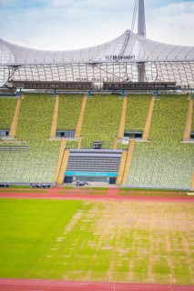 Detailed view of a stadium section with green seating area and roof structure in the background,