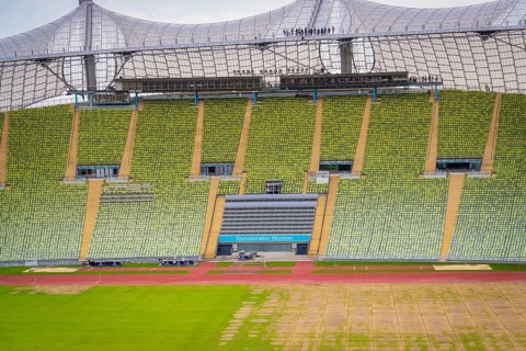 Detailed view of a stadium section with green rows of seats and striking roof background,