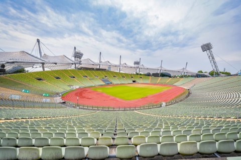 Expansive view of a stadium with red and green colours under a cloudy sky, Olympiapark, Munich,