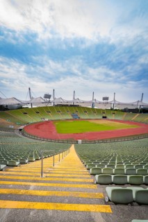 Symmetrical view of a stadium from a staircase with red running track and green stands, Olympic
