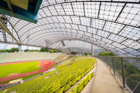 Walk along empty stands in the stadium with a view of a wide playing field, Olympiapark, Munich,
