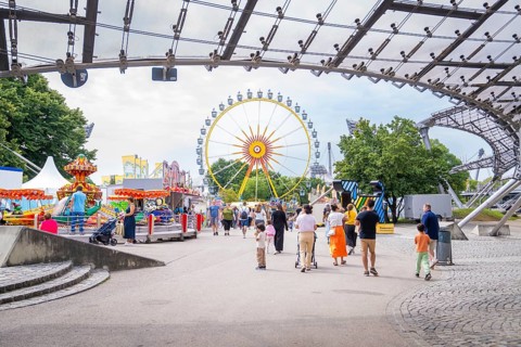 Lively amusement park with Ferris wheel and lots of people strolling around, Olympic Park, Munich,