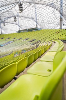 Close-up of empty green seats with a view of a modern glass roof, Olympiapark, Munich, Germany