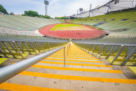 Central view of the stadium from the stairs onto empty stands and red running track, Olympic Park,
