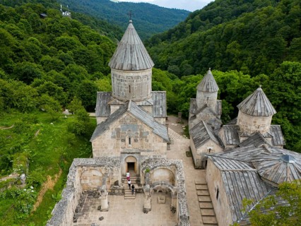 Aerial view of a classical monastery in the middle of dense forests and hilly landscape, aerial