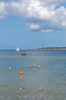 Sailing boat, rubber dinghy, people bathing, in the background the naval memorial in Laboe, Kiel