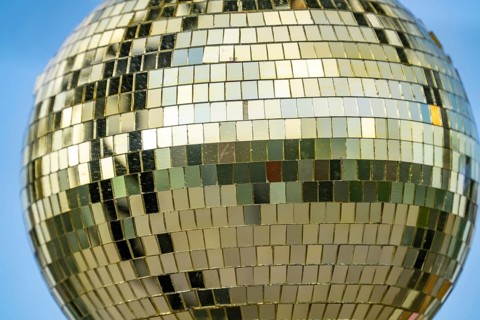 Golden disco ball, small mirrors, distributed like a mosaic, reflect light and create lighting
