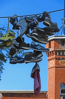Shoes hanging on a leash in the courtyard of a residential home for addicts, each shoe a reminder