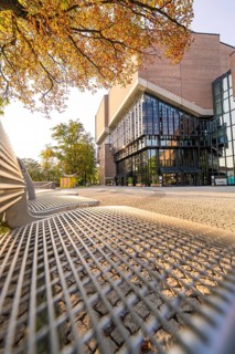 Modern building with glass front, framed by autumnal trees, urban and sunny ambience, Munich,