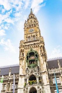 Detailed tower of the town hall with clock and figures under a blue sky, Munich, Germany