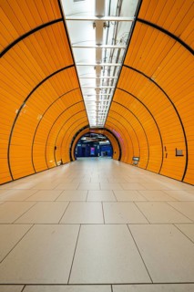 Long, illuminated underground railway tunnel in bright orange, leading into the distance,