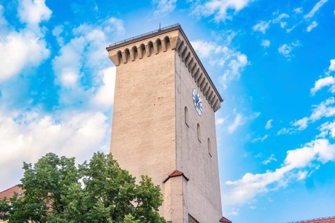 Historic clock tower with clock face in front of a blue sky, Munich, Germany