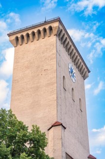 Historic clock tower with clock face in front of a blue sky, Munich, Germany