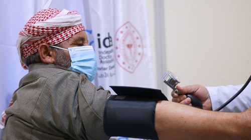 A Syrian doctor wearing a protective mask consults with a displaced patient inside a medical clinic