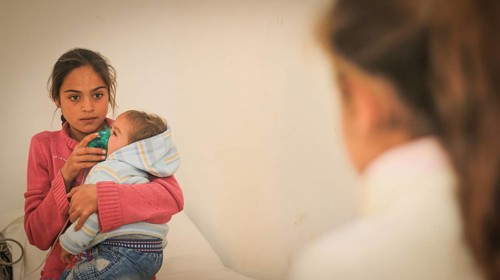 A doctor examining a displaced Syrian child inside a mobile clinic at a refugee camp. Aleppo, Syria