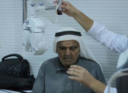 An ophthalmologist performing an eye examination for an elderly displaced man using an