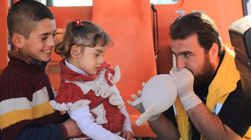 Displaced Syrian children receiving urgent medical intervention inside an ambulance, reflecting the