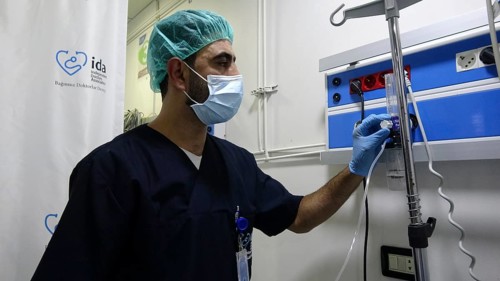 A doctor adjusting the oxygen ventilator settings for a patient inside the intensive care unit