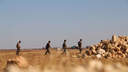 Military fighters carrying a wounded man injured during a battle against ISIS in northern Syria.