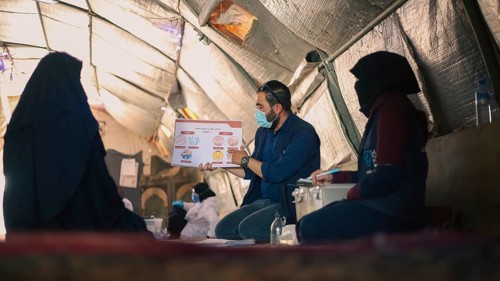 A community health worker giving instructions to refugees on how to deal with the cholera outbreak