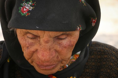 An elderly Syrian refugee looks worn out by war, as displaced people endure difficult conditions in