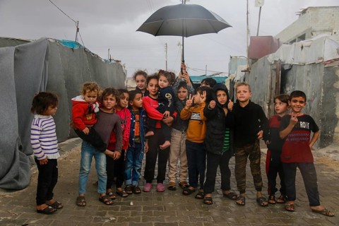 Syrian children inside the refugee camp taking a group photo under the rain on World Children's Day