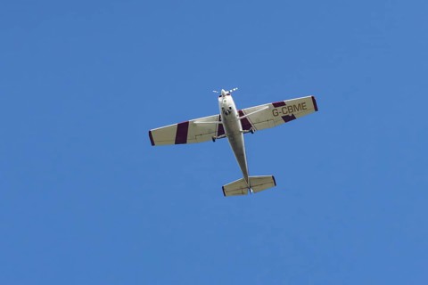 Reims Cessna F172M Skyhawk light aircraft flying in a blue sky, England, United Kingdom