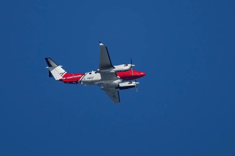 Beech King Air 350 light aircraft of the UK HM Coastguard flying in a blue sky, England, United