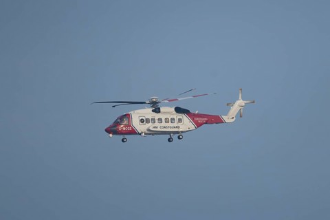 Sikorsky S-92A helicopter of the UK HM Coastguard flying in a blue sky, England, United Kingdom