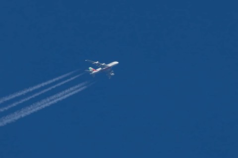 Airbus A380 jet passenger aircraft of Emirates airlines with a vapour trail or contrail flying in a
