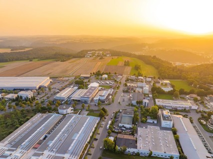 Industrial area in hilly landscape, surrounded by fields, at atmospheric sunset, industrial area