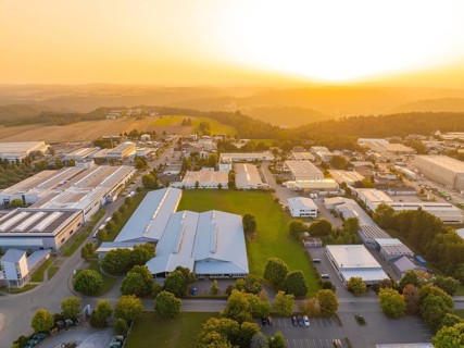 Industrial complex with surrounding green areas and fields at sunset, industrial area Wolfsberg