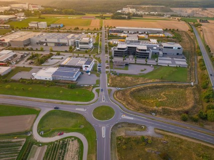 Industrial area with central roundabout, adjacent to fields and modern buildings, industrial area