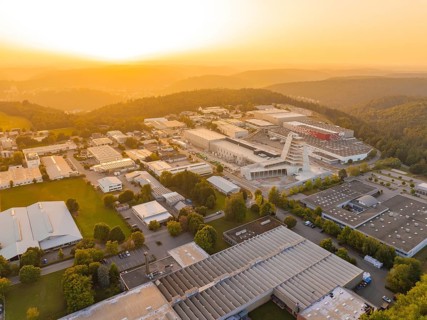 Extensive industrial complex embedded in wooded hills at sunset, industrial area Wolfsberg Nagold,