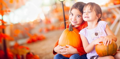 Two girls holding their pumpkins at A pumpkin patch on a fall day
