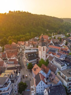 Church tower and town street at sunset, surrounded by hills and trees, Nagold, district of Calw,