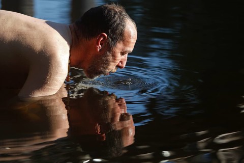 Man in the water during body care while travelling, Müritz National Park, Mecklenburg-Western