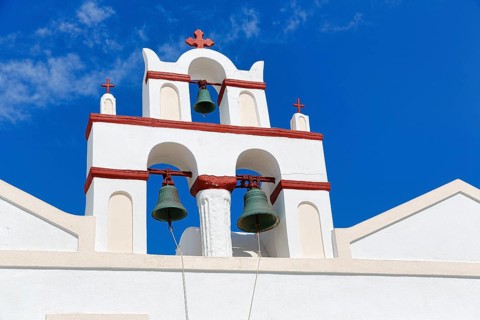 Bell tower of an orthodox church in typical Cycladic architecture with whitewashed walls and red
