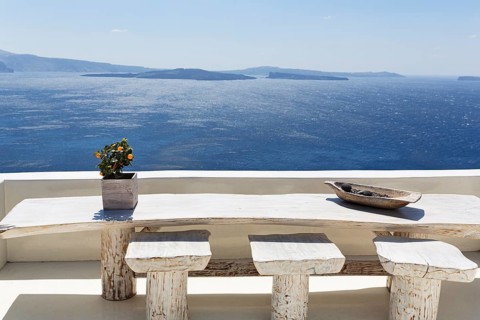 Wooden table on a white terrace by the sea, view of the caldera, Oia, Thira, Santorini, Cyclades,