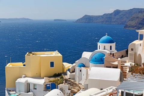 Yellow holiday home by the sea, with typical roof terrace, orthodox church with blue dome, view
