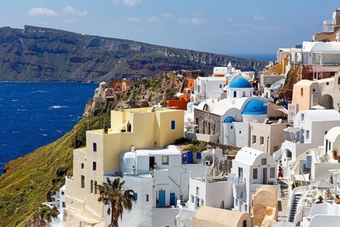 White and colourfully painted holiday homes, orthodox churches with blue domes on the edge of the