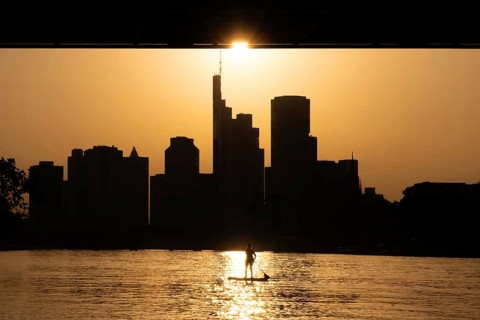 The evening sun stands over the Frankfurt banking skyline while paddlers and rowers navigate the