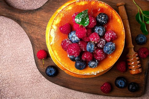 Breakfast, pancakes with berries and honey, top view, homemade, no people, on a wooden background