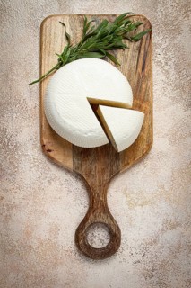 Head of Georgian cheese, Imereti variety, top view, on a cutting board